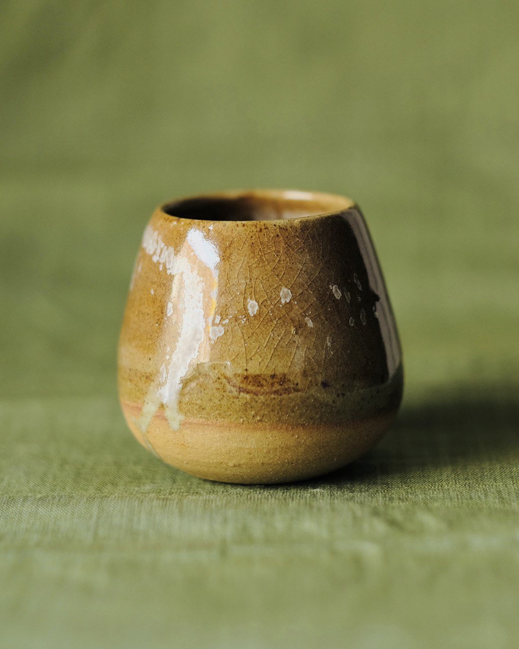 A close shot of a Tamago mug by 22tutucraft on a green table clothe