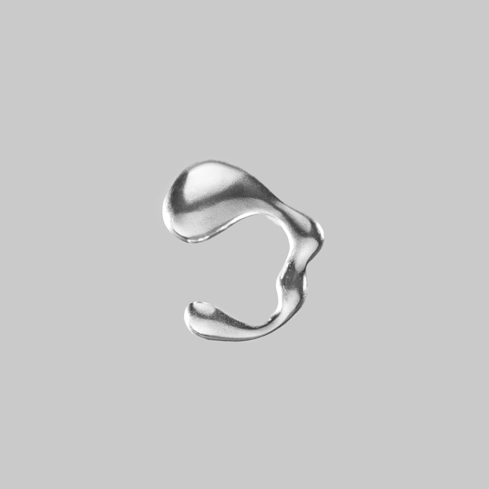 a wavy silver colored ear cuff on a light gray background