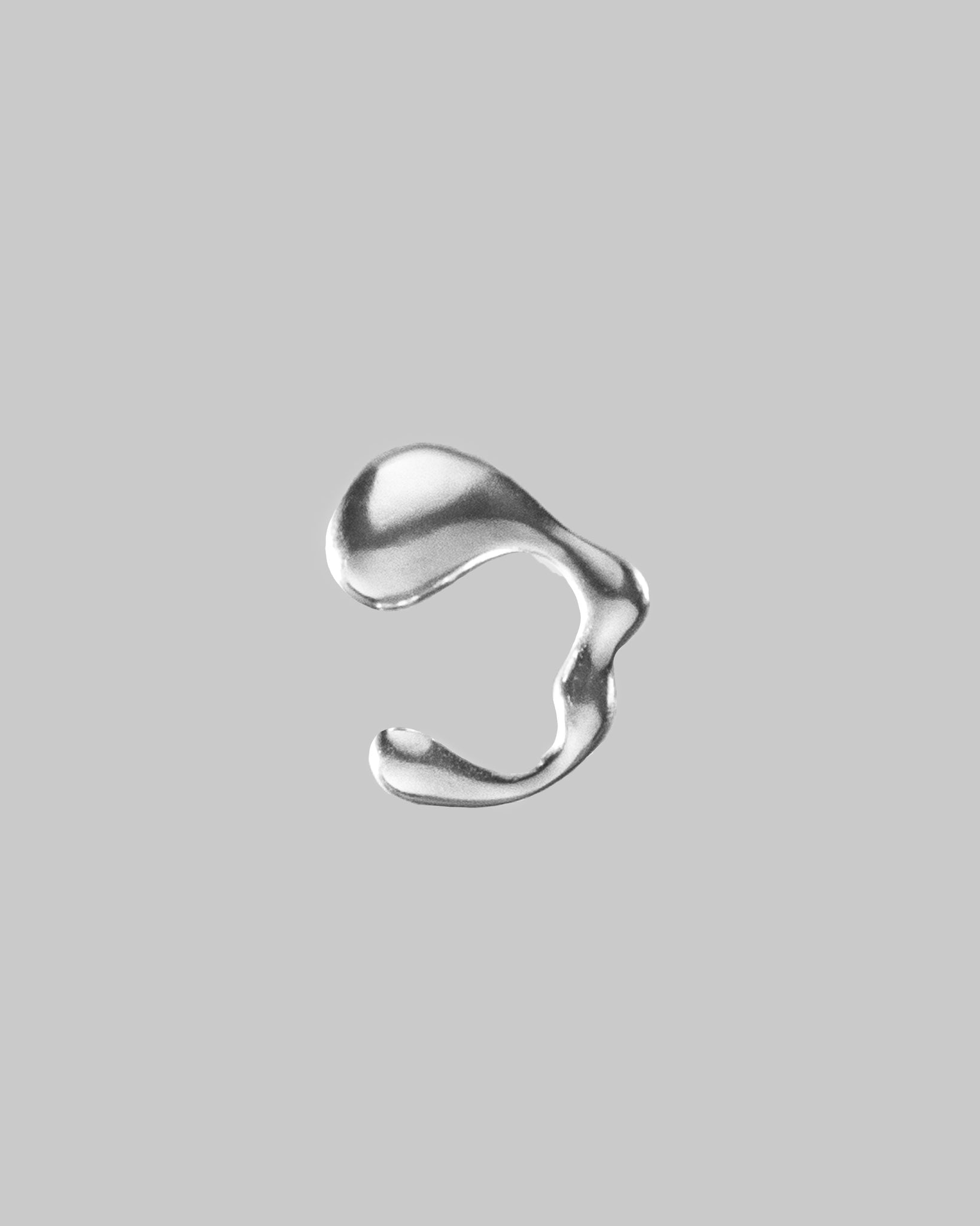 a wavy silver colored ear cuff on a light gray background
